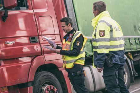 Zwei Polizisten stehen vor einem LKW